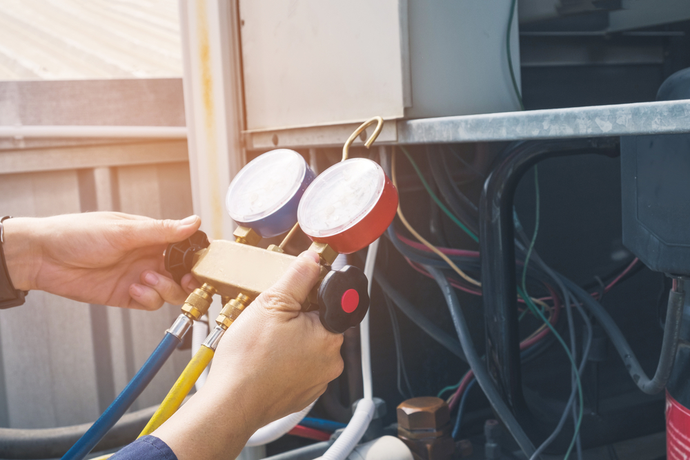Technician performing AC maintenance on a home air conditioning system to keep it running efficiently during summer